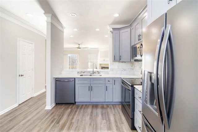 kitchen with a sink, stainless steel appliances, gray cabinetry, and ceiling fan