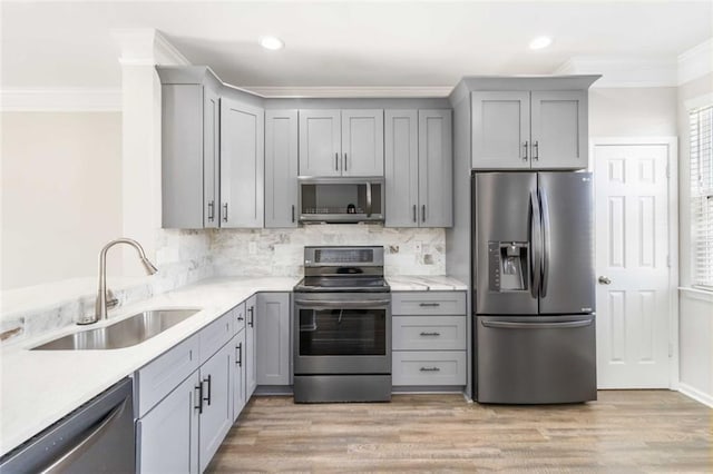 kitchen featuring ornamental molding, appliances with stainless steel finishes, gray cabinetry, and a sink