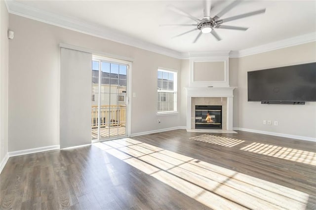 unfurnished living room featuring a ceiling fan, wood finished floors, baseboards, ornamental molding, and a tiled fireplace