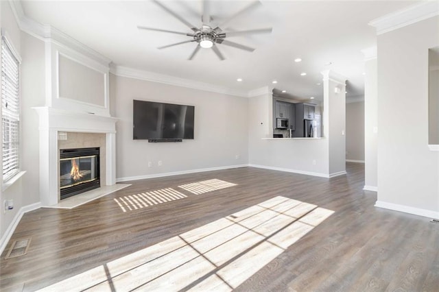 unfurnished living room with ornamental molding, visible vents, a fireplace with flush hearth, and ceiling fan