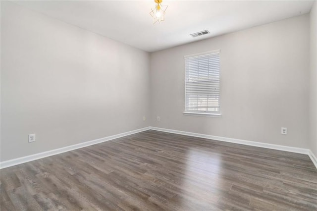 unfurnished room featuring visible vents, baseboards, and dark wood-style floors