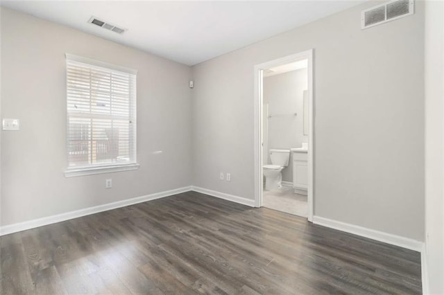 unfurnished room featuring visible vents, baseboards, and dark wood-type flooring