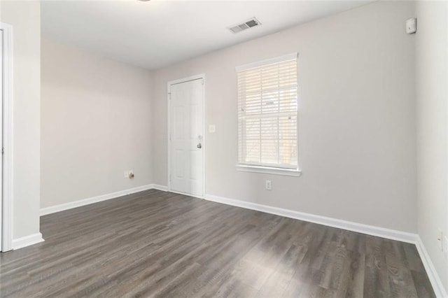 empty room with visible vents, baseboards, and dark wood-style flooring