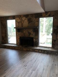 unfurnished living room with hardwood / wood-style flooring and a stone fireplace