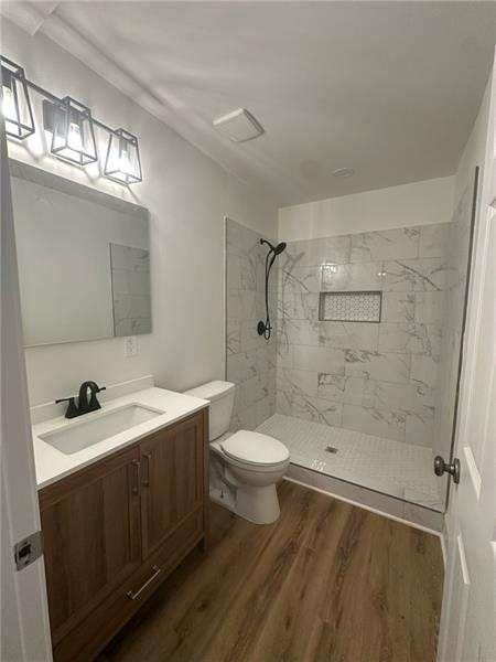 2041 Olive Springs Rd, Marietta, GA 30060 - bathroom featuring toilet, tiled shower, vanity, and wood finished floors