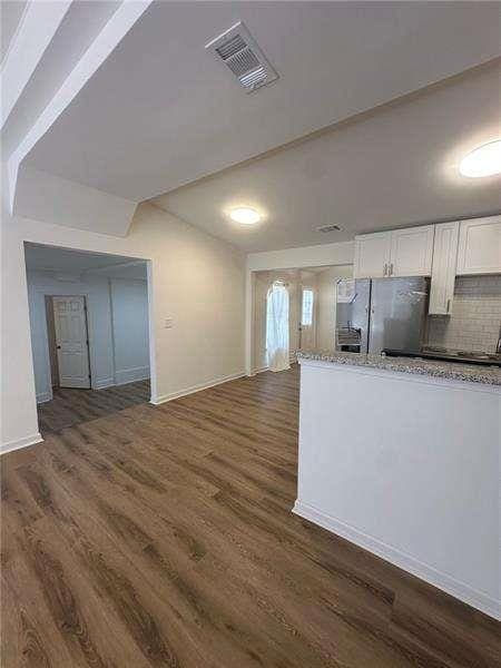 2041 Olive Springs Rd, Marietta, GA 30060 - kitchen featuring refrigerator with ice dispenser, visible vents, white cabinetry, backsplash, and dark wood-style floors