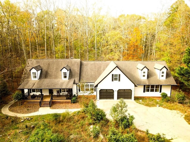 cape cod house featuring a porch and a garage