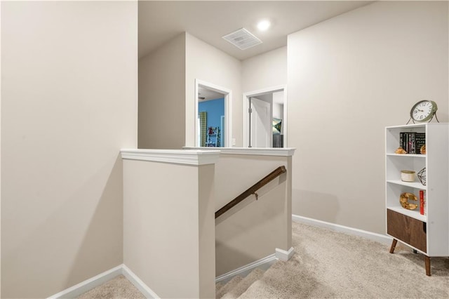 hall with baseboards, visible vents, carpet flooring, and an upstairs landing