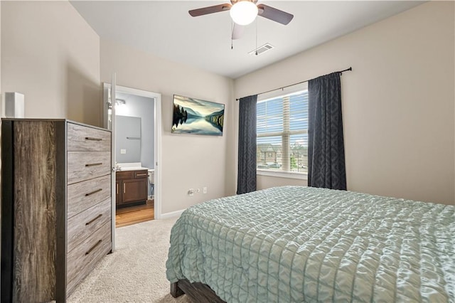 bedroom with a ceiling fan, light colored carpet, visible vents, baseboards, and connected bathroom