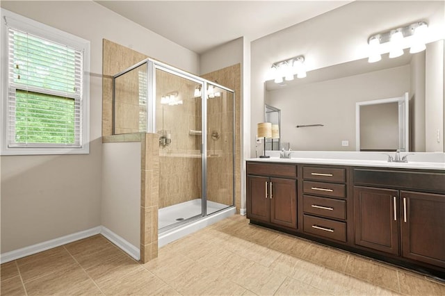 bathroom with double vanity, tile patterned flooring, a stall shower, a sink, and baseboards