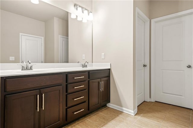 full bath with double vanity, a sink, baseboards, and tile patterned flooring
