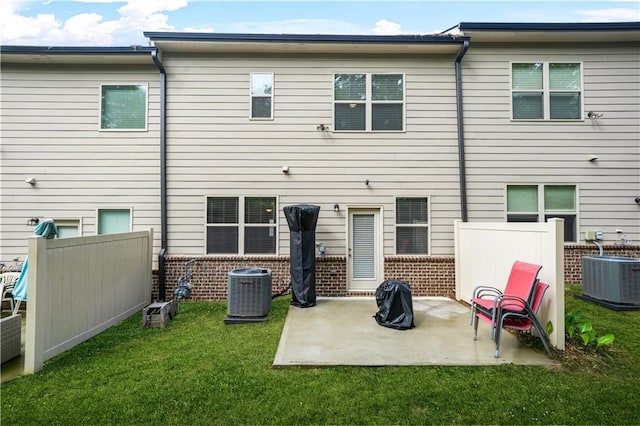 rear view of house with fence, central AC, brick siding, a patio, and a yard