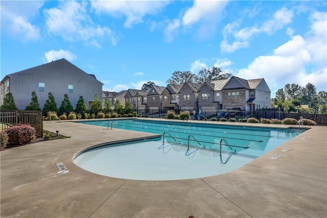 pool with fence, a patio area, and a residential view