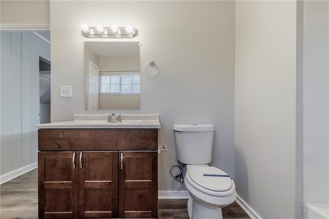 bathroom with vanity, wood finished floors, toilet, and baseboards