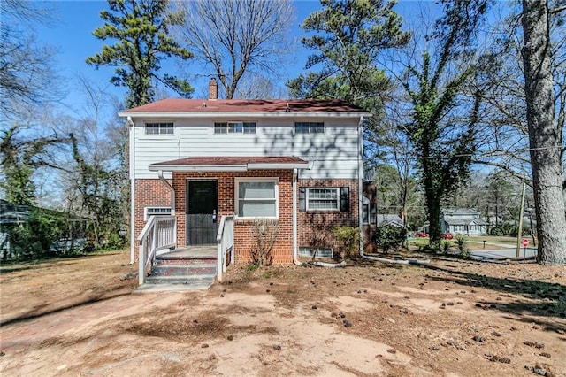 view of front facade featuring brick siding and a chimney