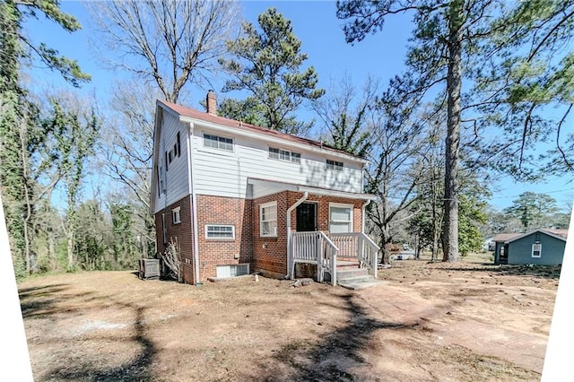 view of front of property featuring a chimney and brick siding