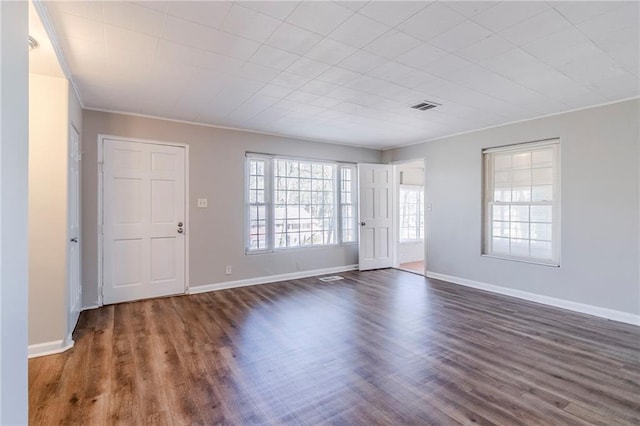 interior space with ornamental molding, dark wood finished floors, visible vents, and baseboards