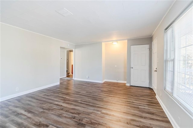 empty room featuring crown molding, wood finished floors, and baseboards