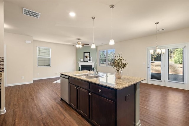 kitchen featuring pendant lighting, stainless steel dishwasher, sink, and an island with sink