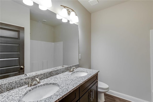 bathroom featuring a shower, vanity, hardwood / wood-style flooring, and toilet