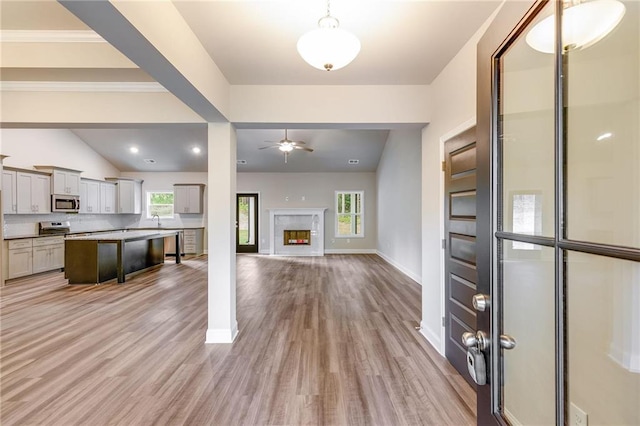 interior space featuring a kitchen breakfast bar, gray cabinets, appliances with stainless steel finishes, and light hardwood / wood-style flooring