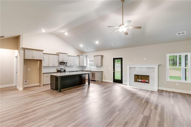 kitchen with a breakfast bar, a center island, gray cabinets, tasteful backsplash, and stainless steel appliances