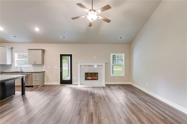 unfurnished living room with a high end fireplace, light hardwood / wood-style floors, and a healthy amount of sunlight