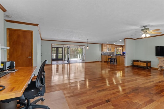 office space with french doors, crown molding, ceiling fan, light wood-type flooring, and a textured ceiling