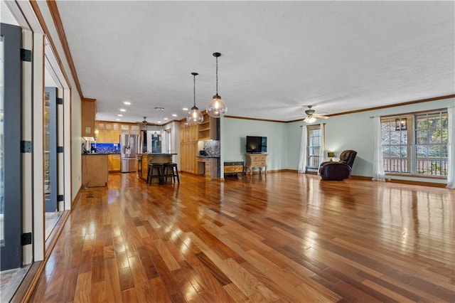 unfurnished living room with light hardwood / wood-style floors, ceiling fan, and crown molding