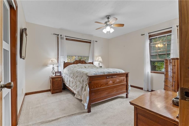 bedroom featuring ceiling fan, light colored carpet, and multiple windows