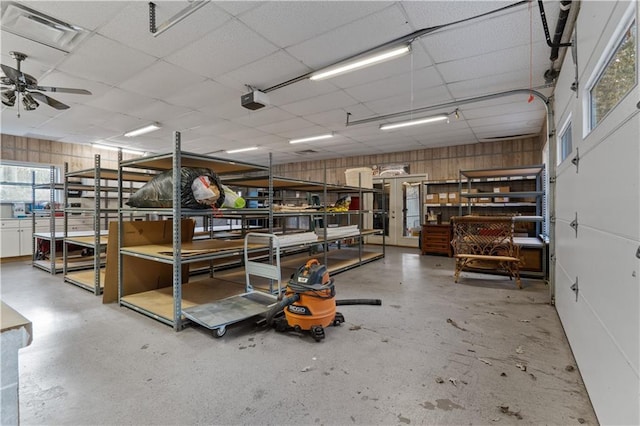 interior space featuring a garage door opener, ceiling fan, and wooden walls