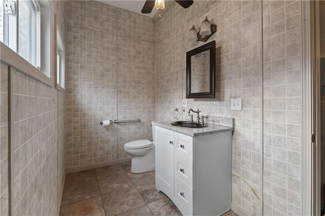 bathroom featuring vanity, toilet, tile walls, and ceiling fan