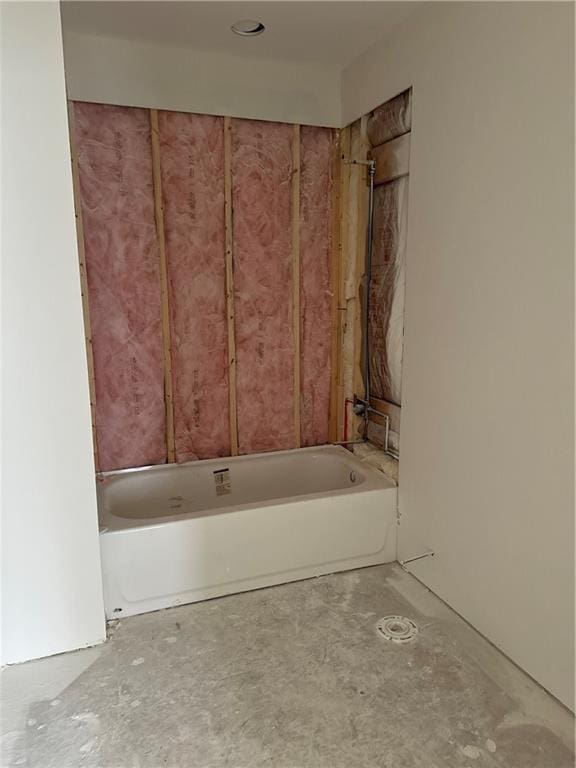 bathroom with a tub and concrete floors