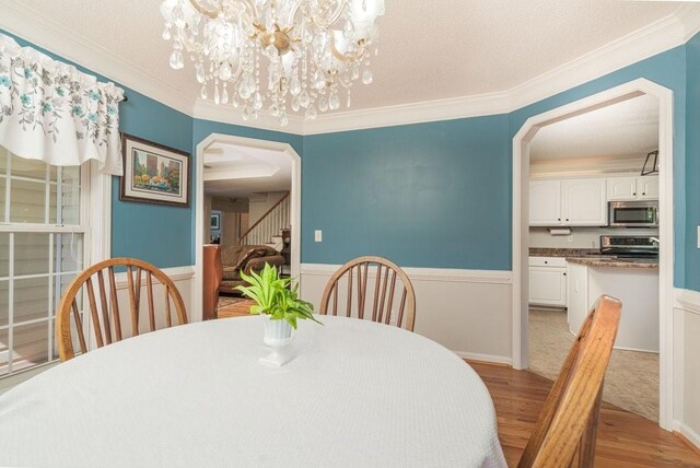 dining room with an inviting chandelier, light hardwood / wood-style floors, and ornamental molding