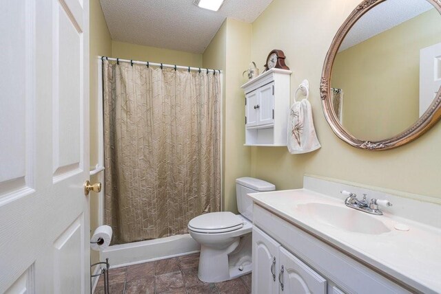 bathroom with vanity, curtained shower, toilet, and a textured ceiling