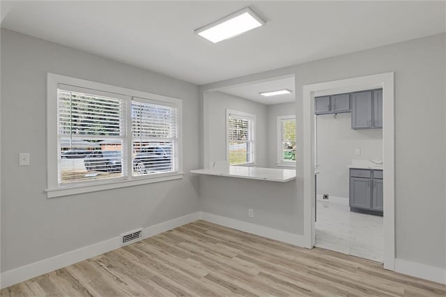 unfurnished dining area with light wood finished floors, visible vents, and baseboards