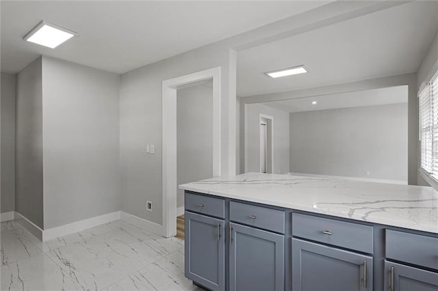 kitchen featuring light stone counters, baseboards, marble finish floor, and gray cabinetry