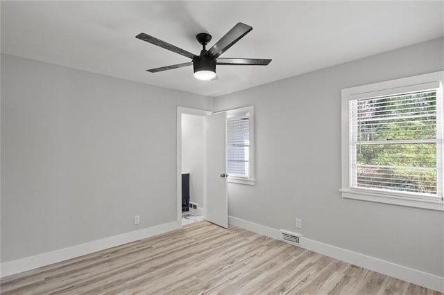 unfurnished room featuring light wood-type flooring, visible vents, baseboards, and a ceiling fan