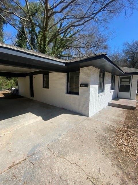 view of property exterior featuring a carport, driveway, and brick siding