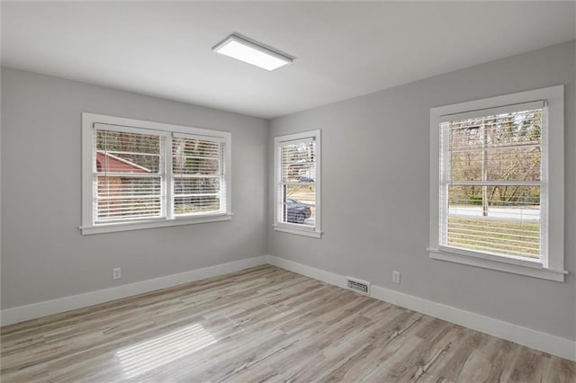 unfurnished room with visible vents, baseboards, and wood finished floors