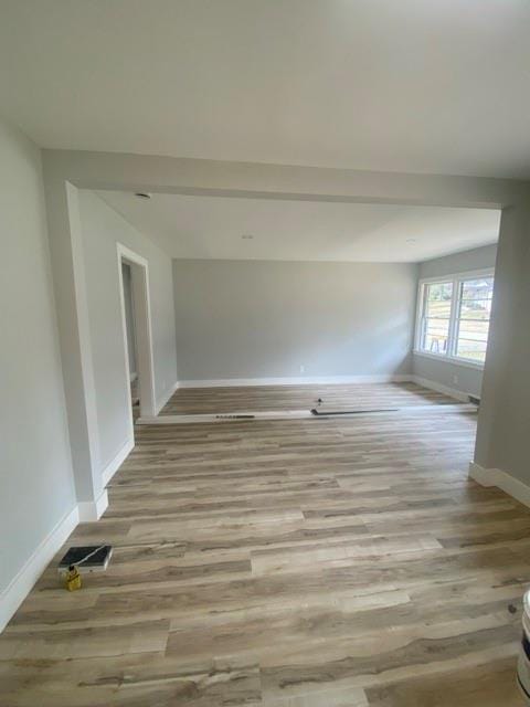 empty room featuring visible vents, baseboards, and light wood-style floors