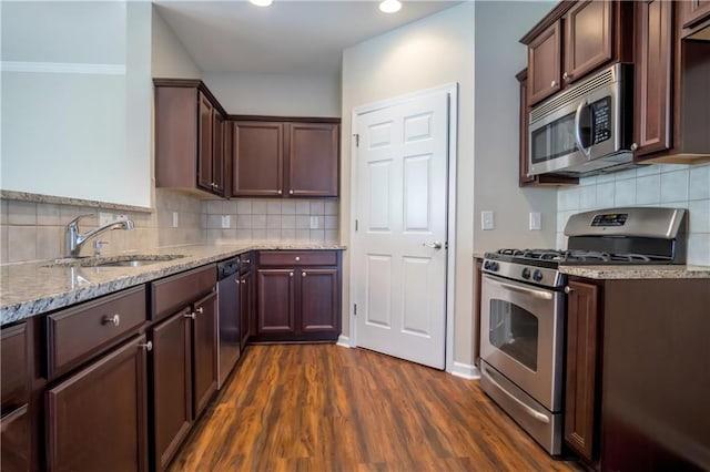 kitchen featuring sink, light stone counters, appliances with stainless steel finishes, dark hardwood / wood-style floors, and backsplash