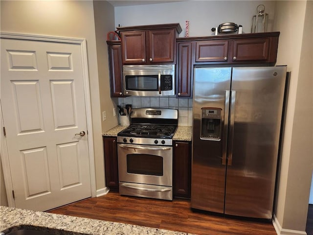 kitchen with light stone counters, stainless steel appliances, dark hardwood / wood-style floors, and tasteful backsplash