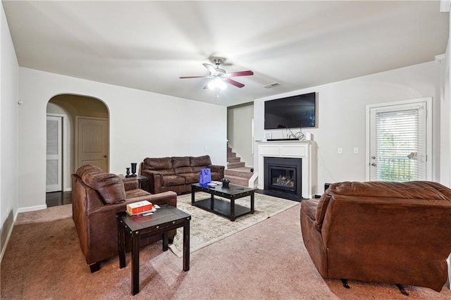 1417 Sterlingbrooke Dr, Powder Springs, GA 30127 - living area with light carpet, a ceiling fan, arched walkways, and a glass covered fireplace