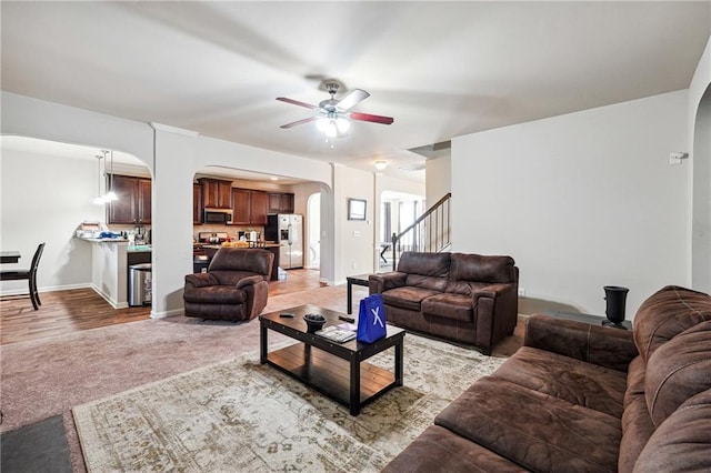 1417 Sterlingbrooke Dr, Powder Springs, GA 30127 - living area with arched walkways, a ceiling fan, light colored carpet, stairs, and baseboards