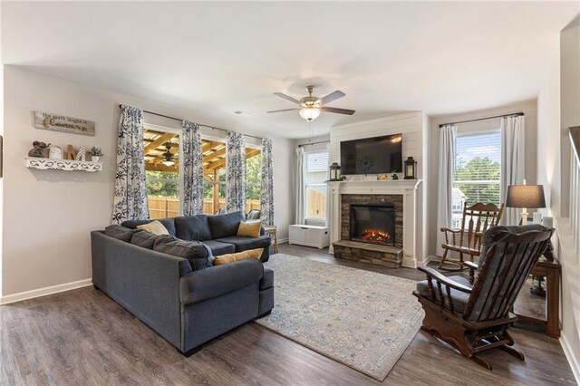 living room with ceiling fan, a stone fireplace, and dark hardwood / wood-style flooring