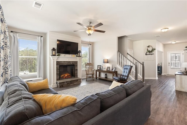 living room with hardwood / wood-style floors, ceiling fan, and a stone fireplace