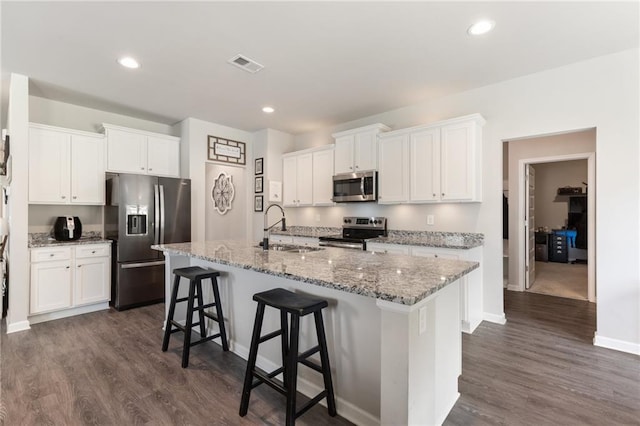 kitchen featuring a kitchen island with sink, white cabinets, sink, a breakfast bar area, and stainless steel appliances