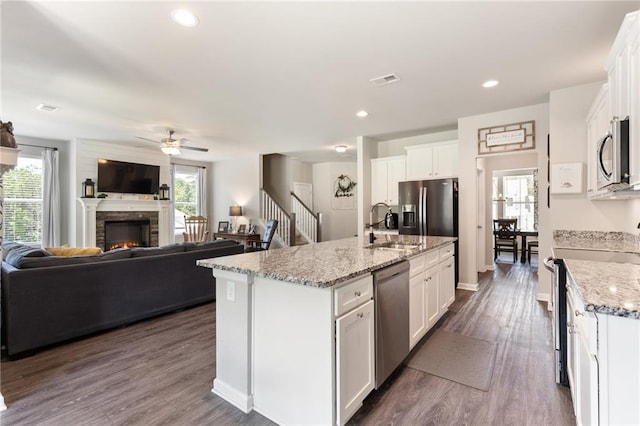 kitchen featuring white cabinets, stainless steel appliances, and an island with sink