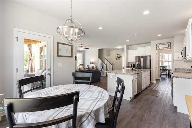 dining area featuring dark hardwood / wood-style flooring, ceiling fan with notable chandelier, and sink